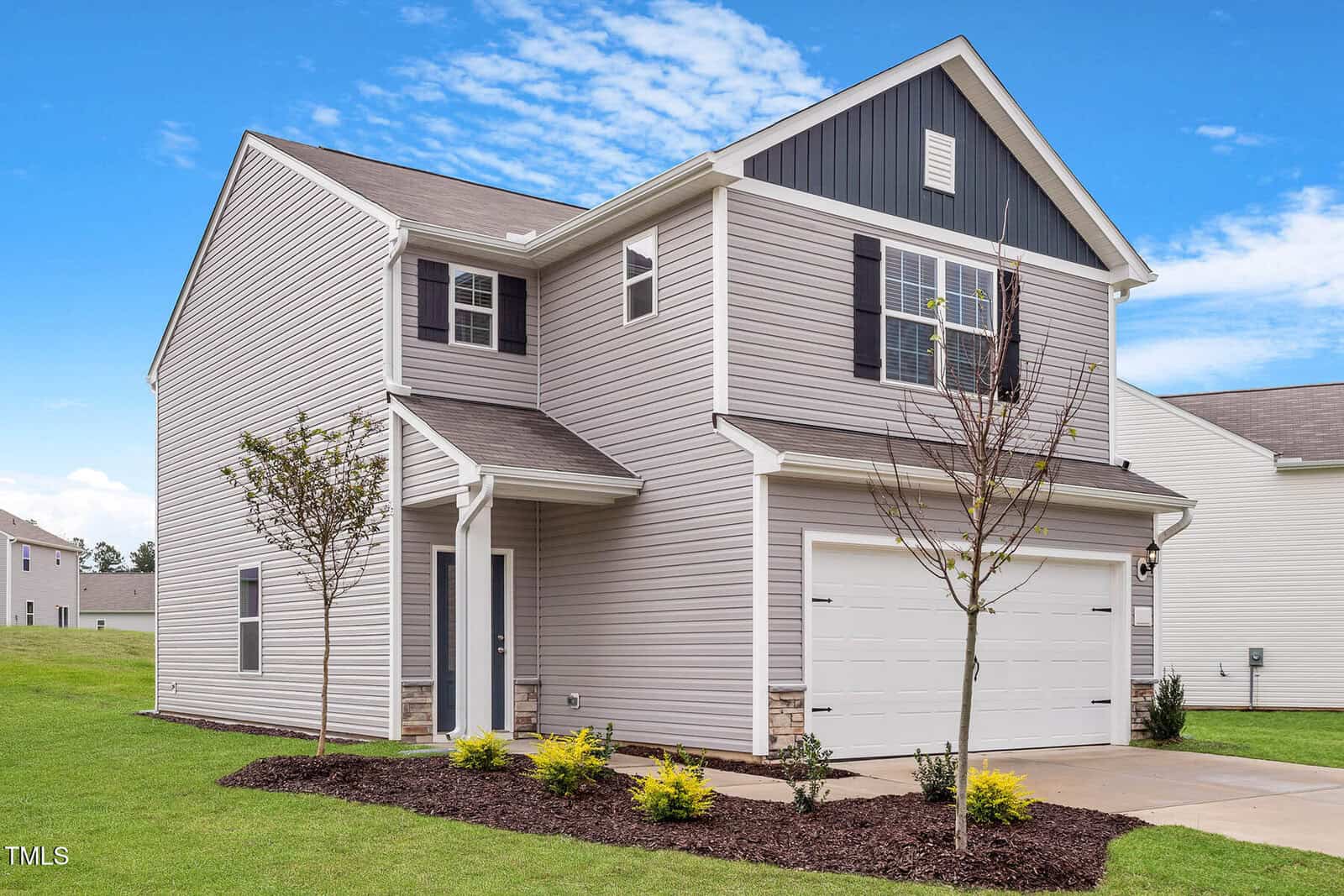 Located at 604 Rhino Bend, this two-story, modern gray house with white trim exudes elegance. It features a gabled roof, double garage doors, and a small front garden with young trees and shrubs. The neatly maintained lawn adds charm under Oxford's clear blue sky.