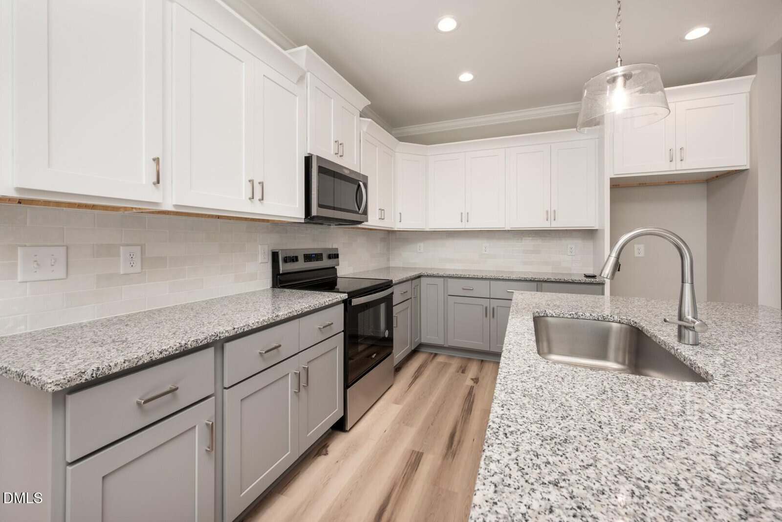 Modern kitchen with white upper cabinets, gray lower cabinets, granite countertops, stainless steel appliances, an electric stove, built-in microwave, tile backsplash, wood-style flooring, and a double-basin sink in the island.