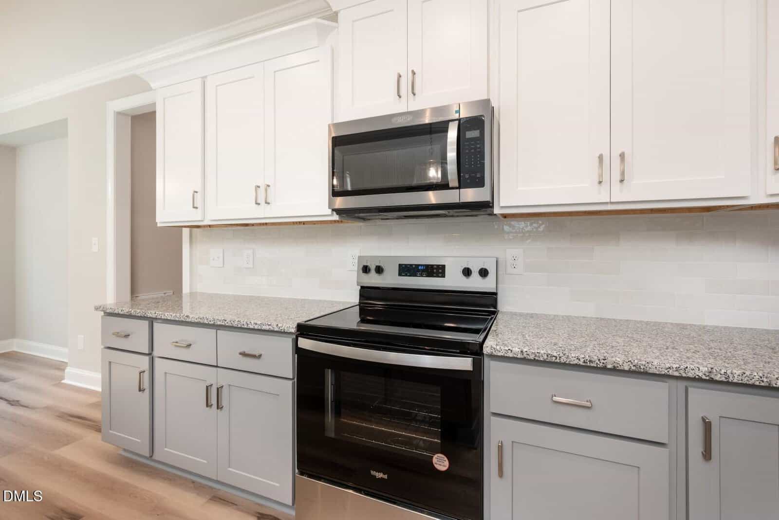 Modern kitchen with white upper cabinets, gray lower cabinets, granite countertops, a stainless steel oven and microwave, and a white subway tile backsplash.