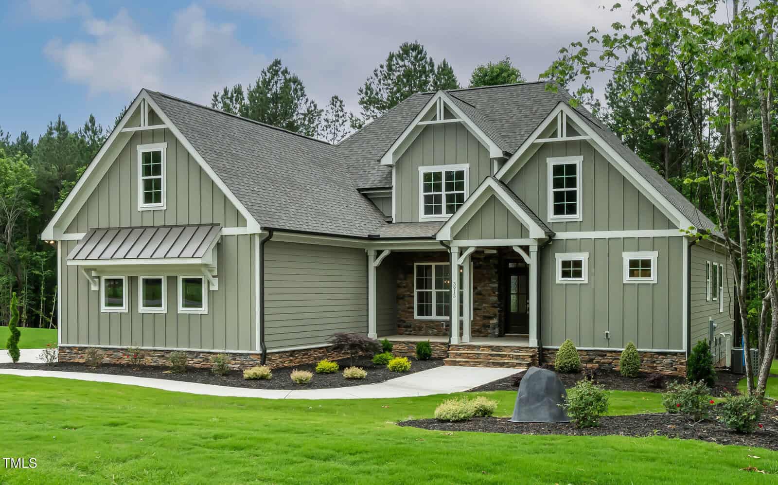 A modern, single-family house at 3913 Cedar Knolls in Youngsville features gray siding, white trim, and a gabled roof on a well-manicured lawn with shrubs and a stone path, surrounded by trees under a partly cloudy sky.