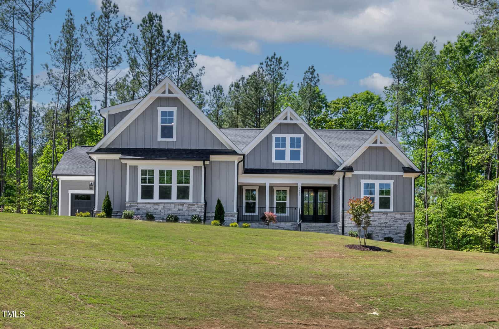 A modern, gray two-story house with white trim and a front porch sits on a large grassy lawn at 3925 Cedar Knolls Drive in Youngsville, surrounded by tall trees under a partly cloudy sky.