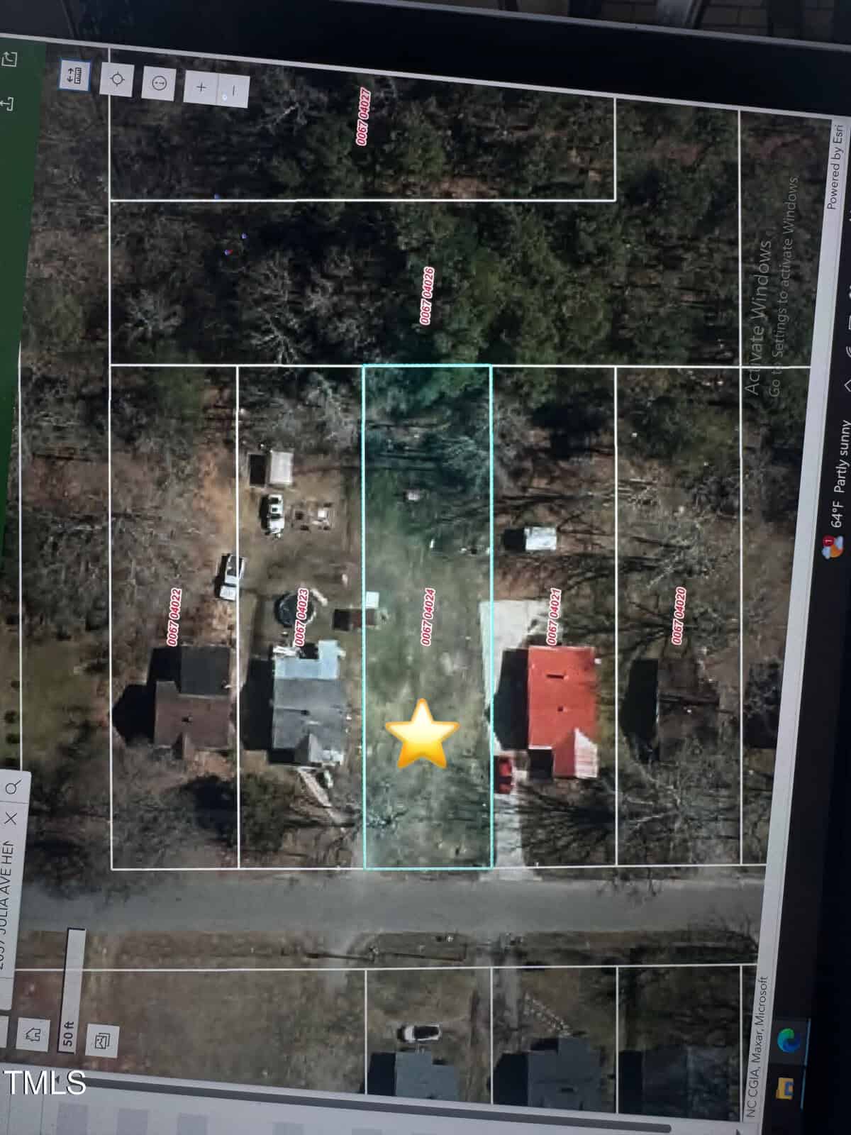 A satellite map view shows a residential area with several houses. The properties are outlined, and a yellow star is placed on one lot towards the center. Trees surround the area, and a street runs horizontally at the bottom.