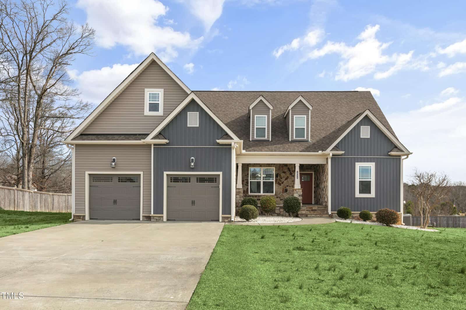 Located at 1044 Butterfly Circle in Wake Forest, this two-story suburban home combines gray and stone siding with a gabled roof. It features dual garage doors and a concrete driveway, while the front yard boasts landscaped shrubs and grass under a partly cloudy sky.
