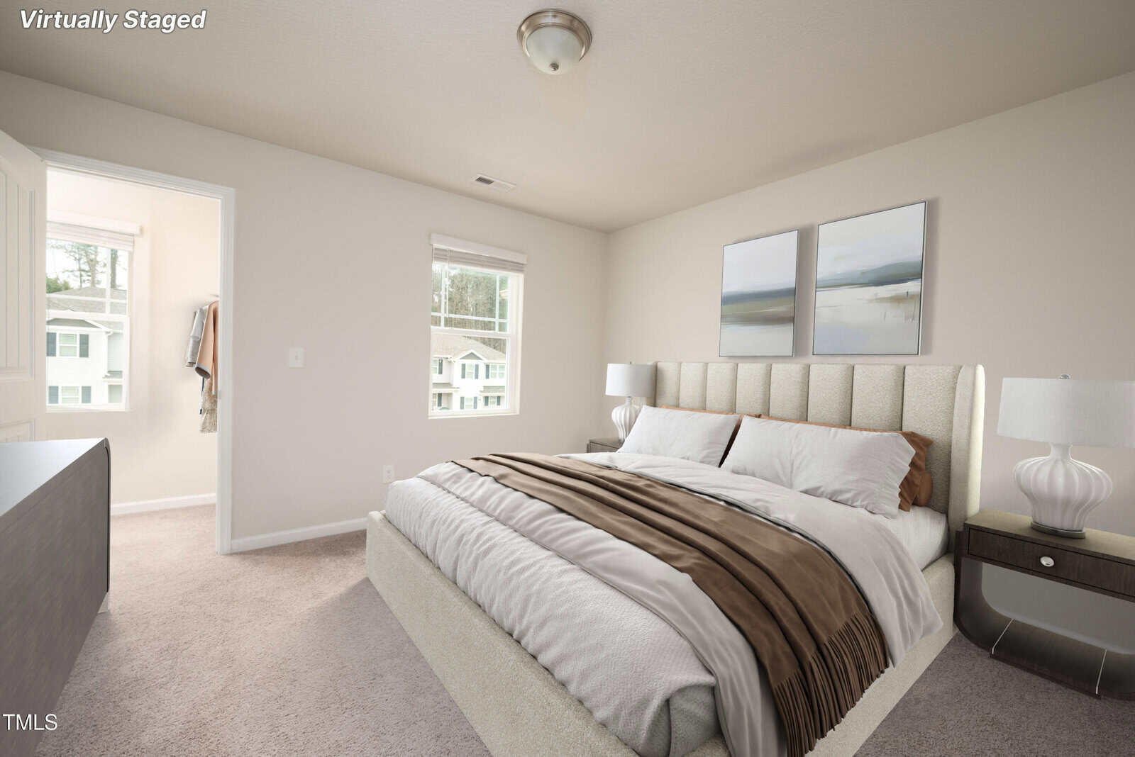 A virtually staged bedroom features a large bed with white and brown bedding, two nightstands with lamps, two wall art pieces above the bed, beige carpet, and windows showing an exterior view.