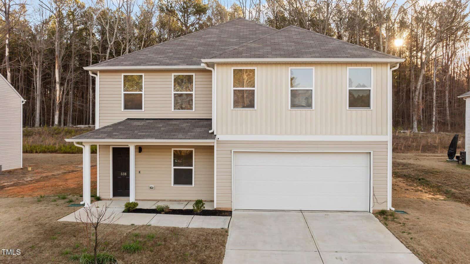 A charming two-story house at 538 E Waycliff Road, Henderson, with beige siding and a gray roof. It boasts a covered front porch, five front-facing windows, and a double garage. The home is set in an undeveloped lawn and backs onto a serene wooded area.
