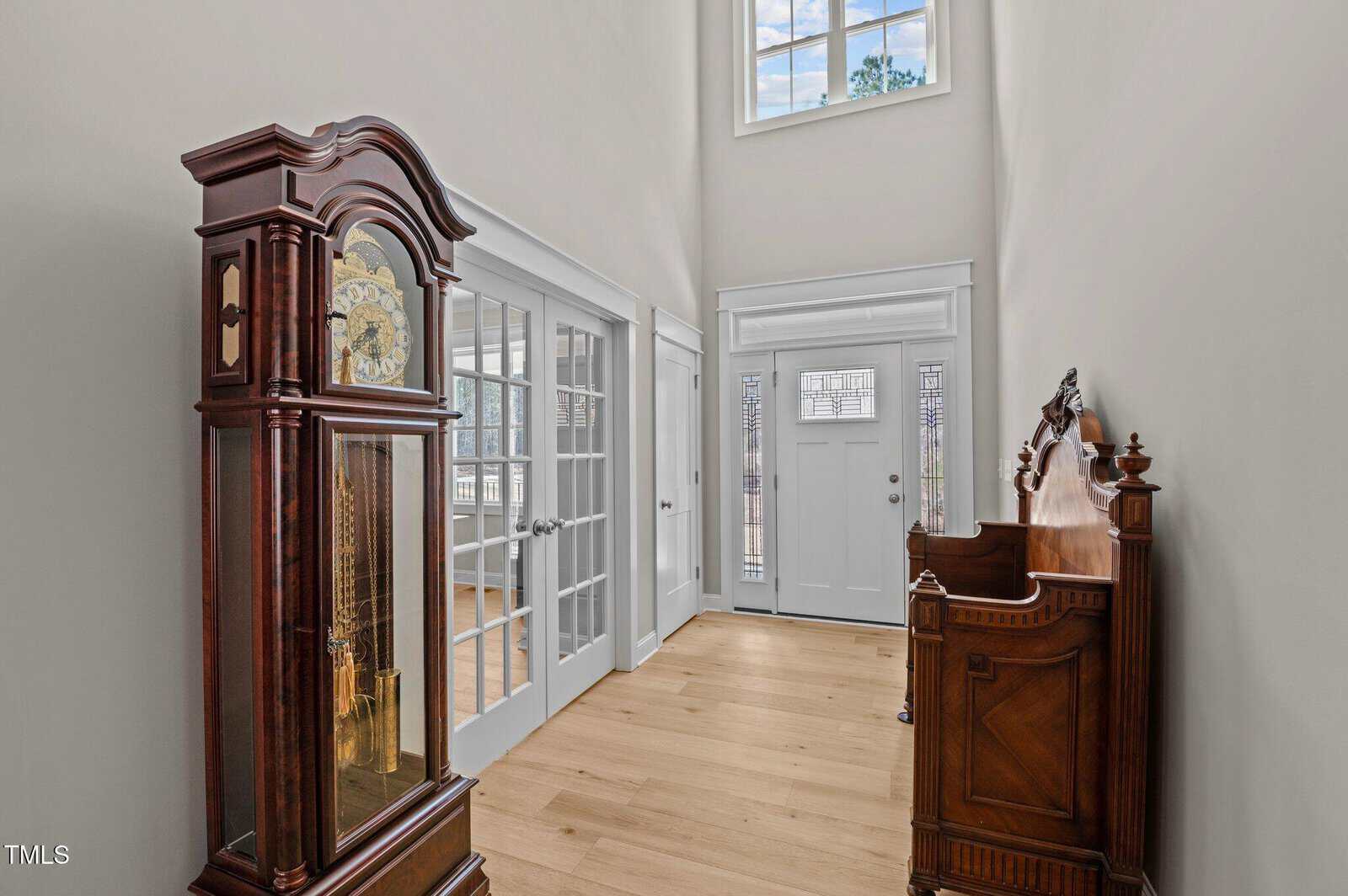 A room with a grandfather clock and a bench.