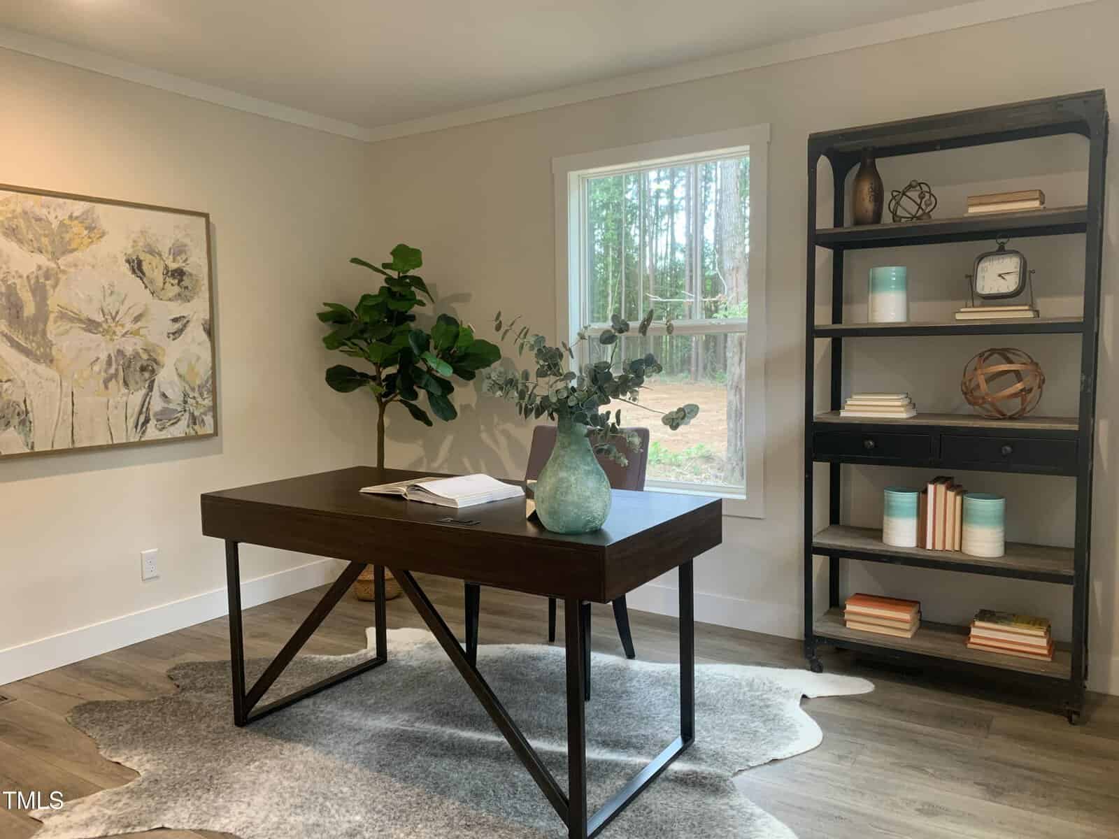 A modern home office with a dark wood desk, a green plant in a vase, a large wall painting, a tall bookshelf with books and decor, and a window showing trees outside. A gray rug is beneath the desk.