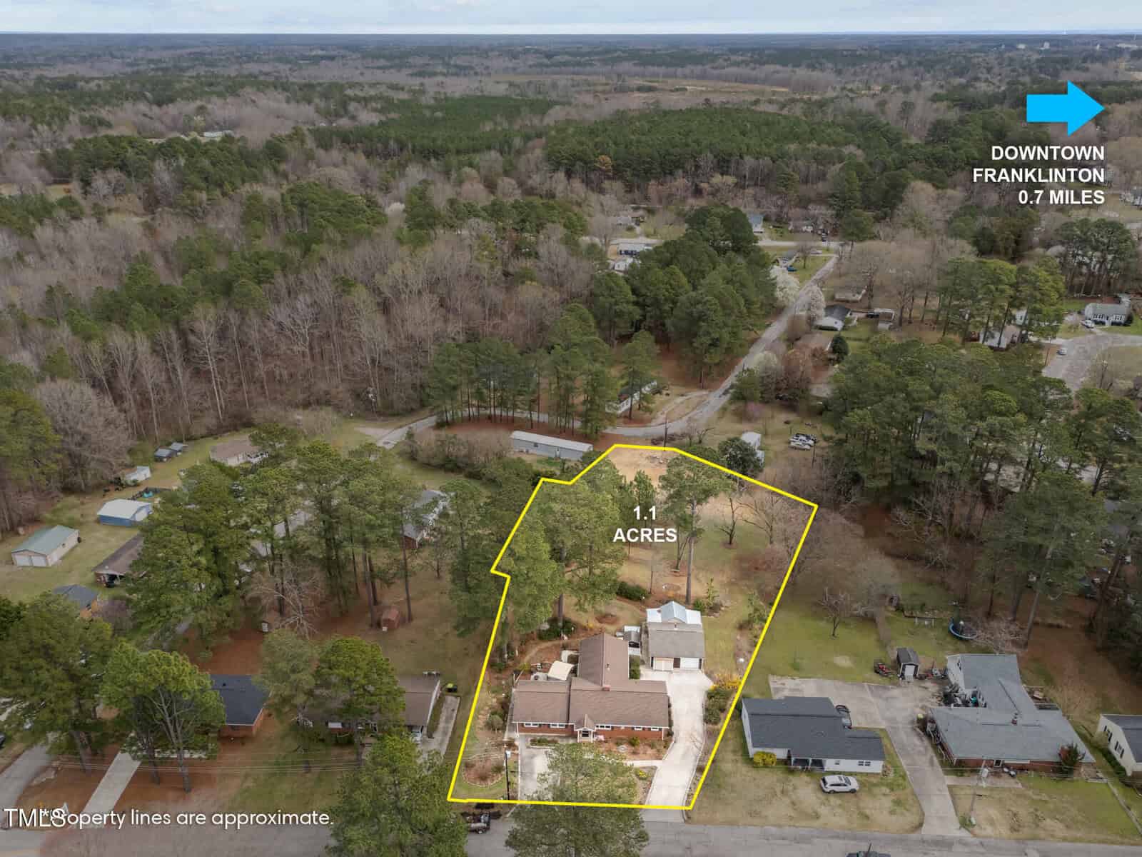 Aerial view of a residential property at 412 N Cheatham Street, Franklinton, outlined in yellow and labeled as 1.1 acres. The image includes nearby homes, trees, and a blue arrow indicating downtown Franklinton is just 0.7 miles away.