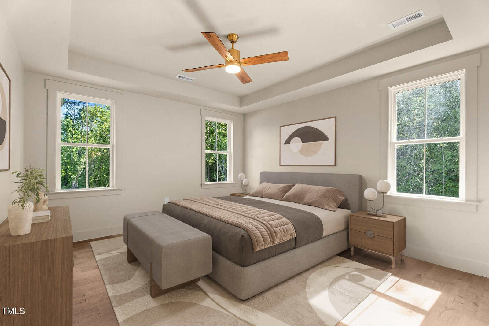 A bright bedroom with a bed, two nightstands, a bench, dresser, abstract wall art, ceiling fan, and large windows letting in natural light.