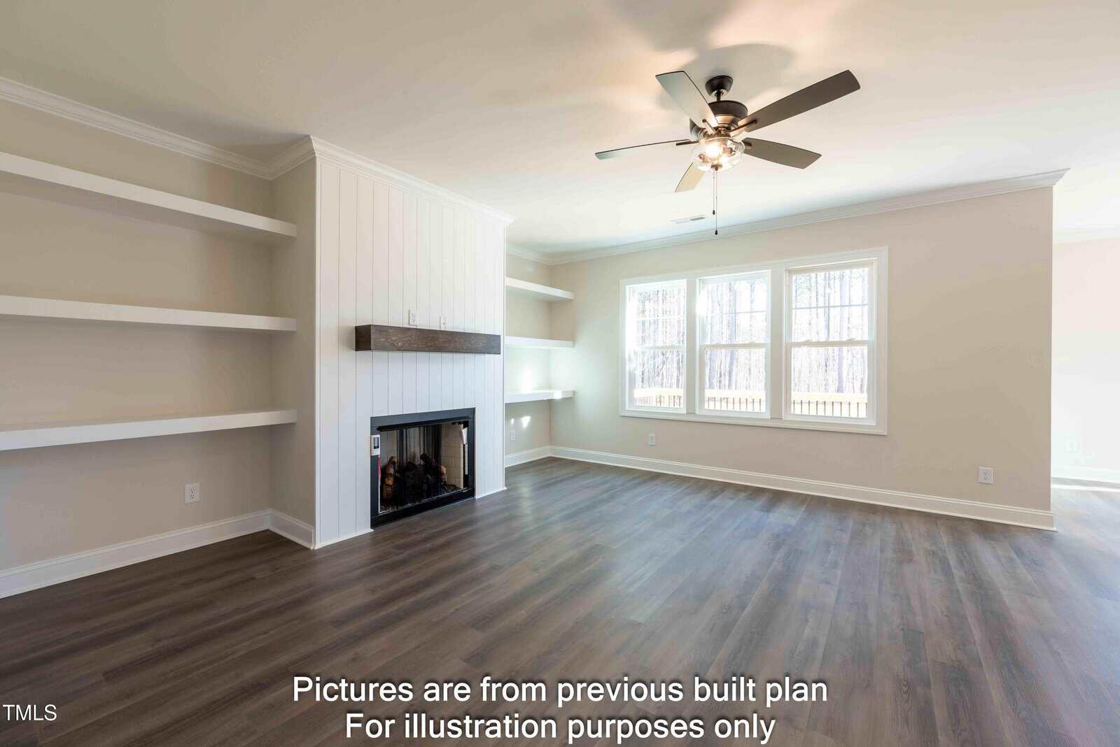 Bright, empty living room with light walls, built-in shelves, a fireplace, ceiling fan, and large windows. Text at the bottom reads: “Pictures are from previous built plan. For illustration purposes only.”.