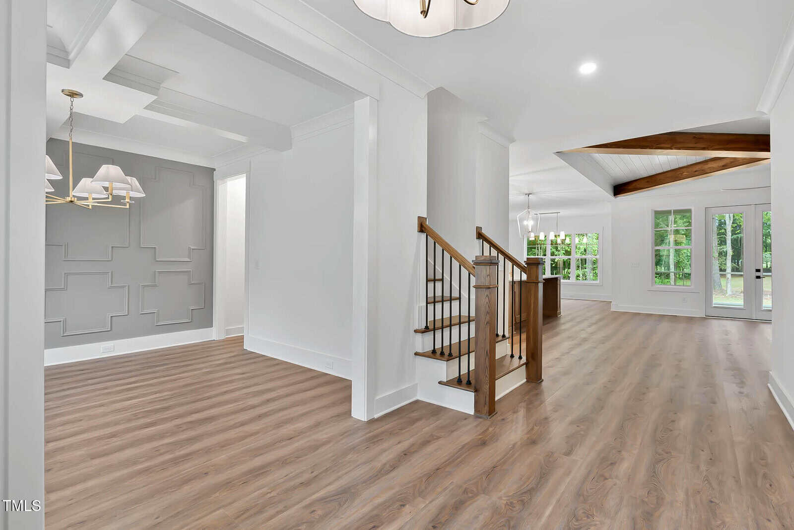 A white and grey room with wood floors and stairs.