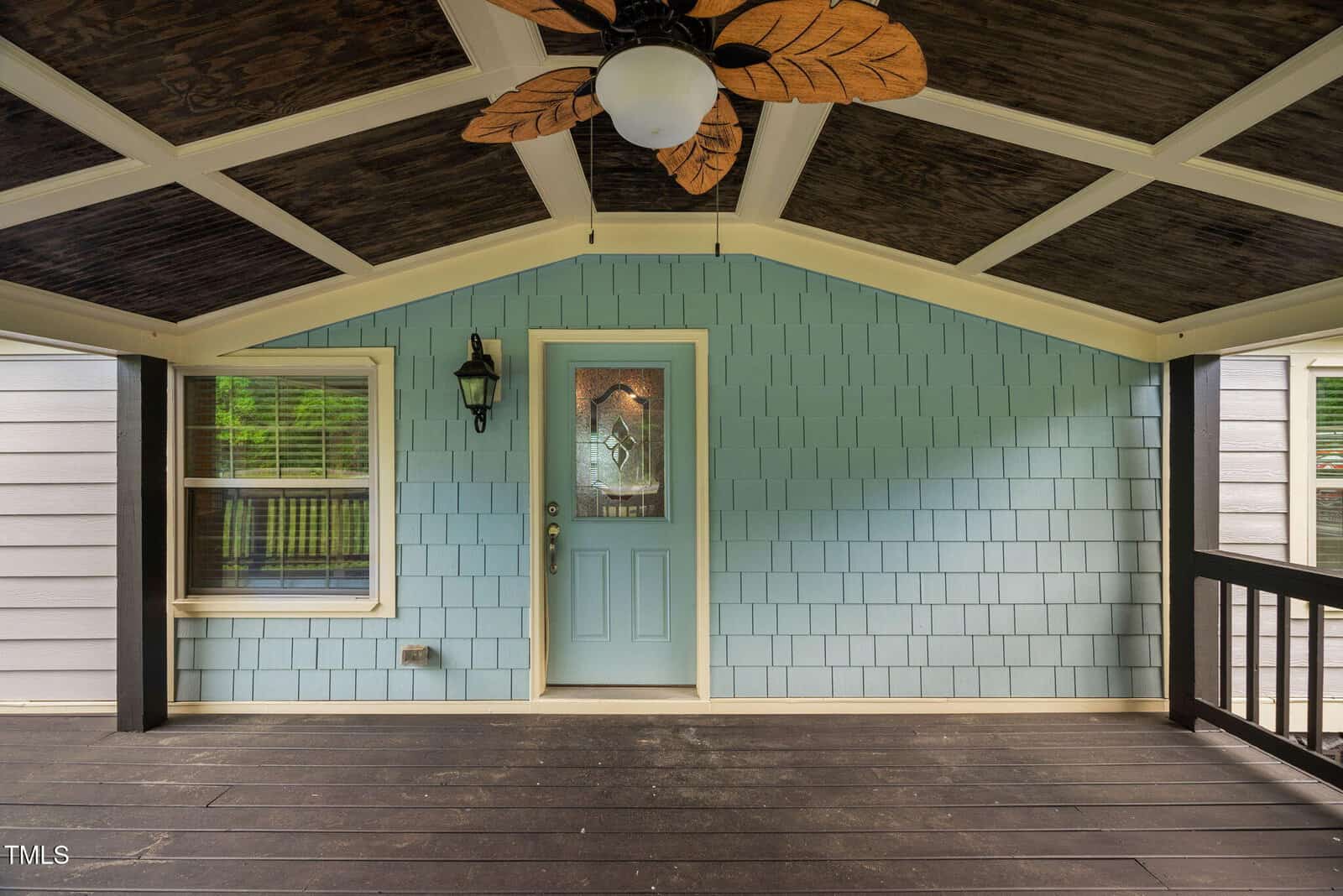 A porch with a ceiling fan and a blue door.