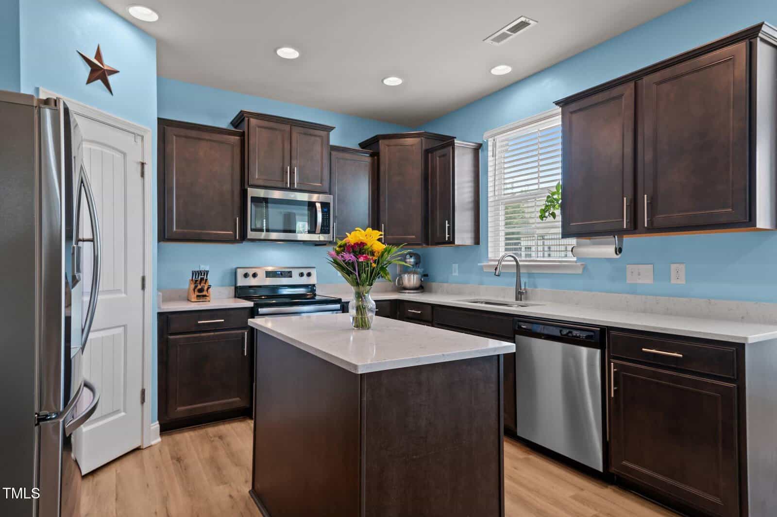 A kitchen with a marble island and stainless steel appliances.