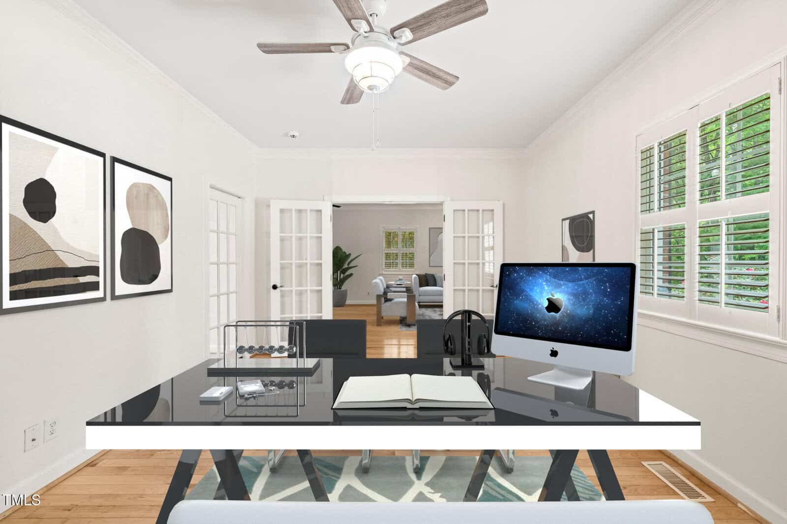 A modern home office with a black and white desk, an iMac, open notebook, Abacus, and headphones. Artwork hangs on the wall, and French doors open to another room with a sofa and plants. White shutters cover the windows.