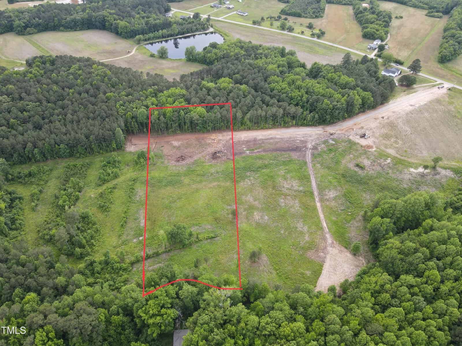 Aerial view of a large, rectangular plot of cleared land at 4 Old Hwy US 64 in Zebulon, outlined in red and surrounded by dense green trees and grassy areas, with roads and buildings visible in the background.