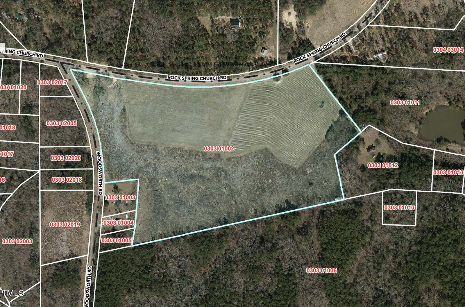 Aerial view of a large, irregularly shaped parcel of land outlined in blue, bordered by Rock Springs Church Road at the top, surrounded by wooded areas and other marked property lines.
