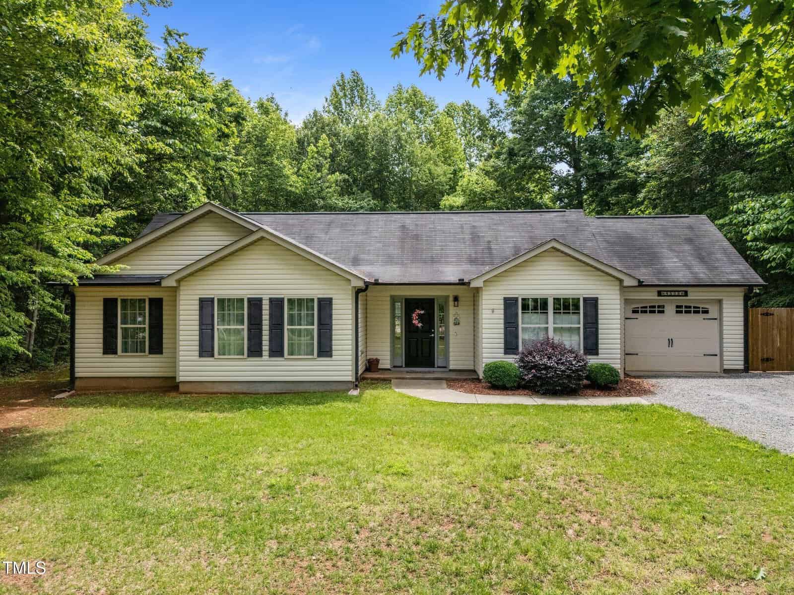 Charming single-story house at 4508 Alice Drive, Oxford, with light-colored siding, black shutters, an attached garage, and a dark roof. Enjoy a front lawn with a gravel driveway and trees surrounding the property.