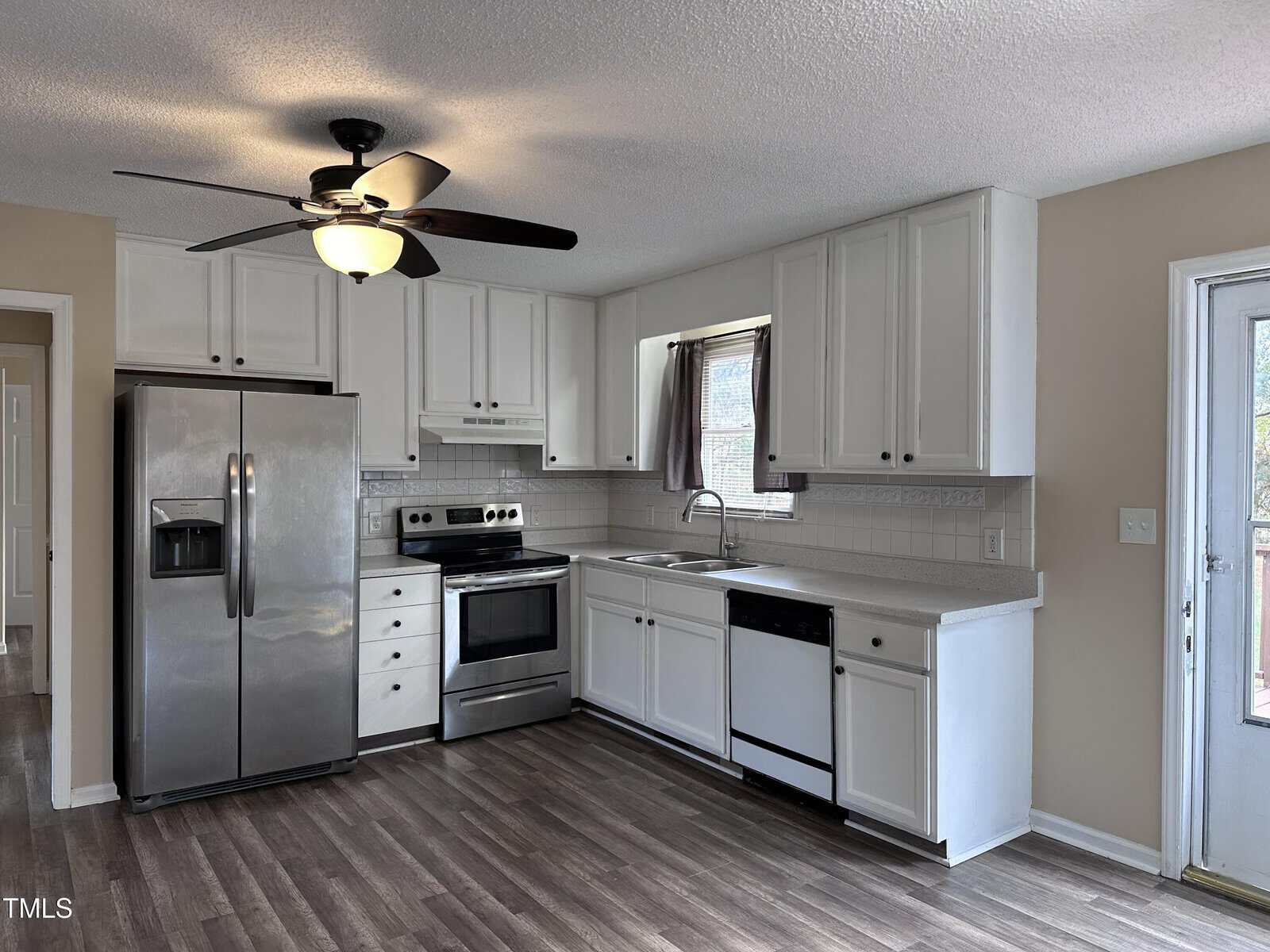 A kitchen with a ceiling fan and a refrigerator.