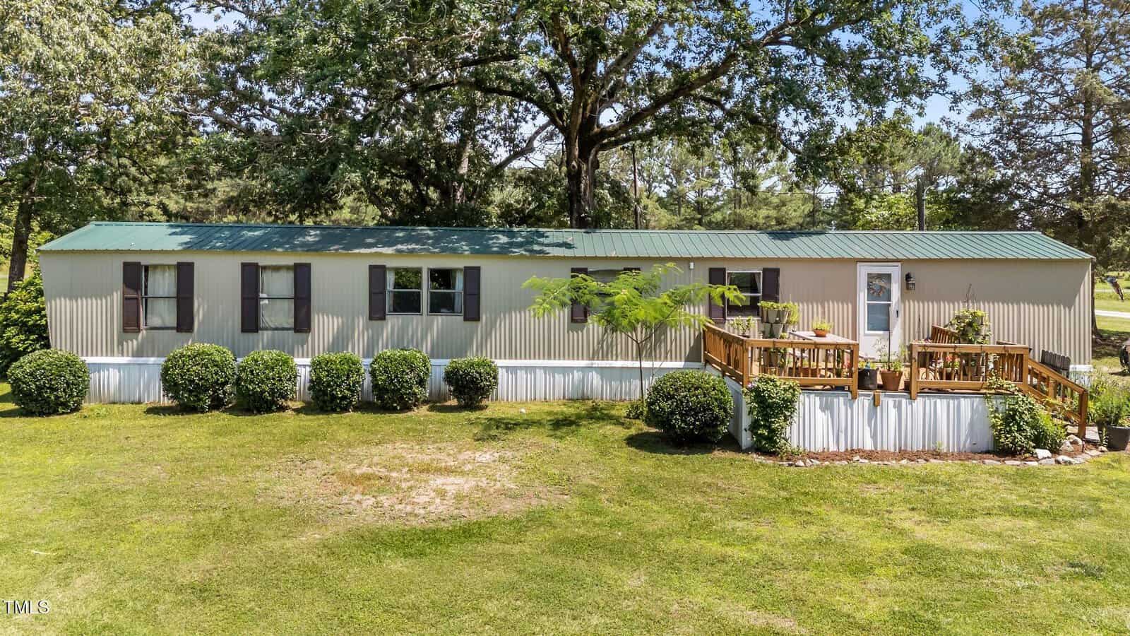 A mobile home with a deck and a lawn.