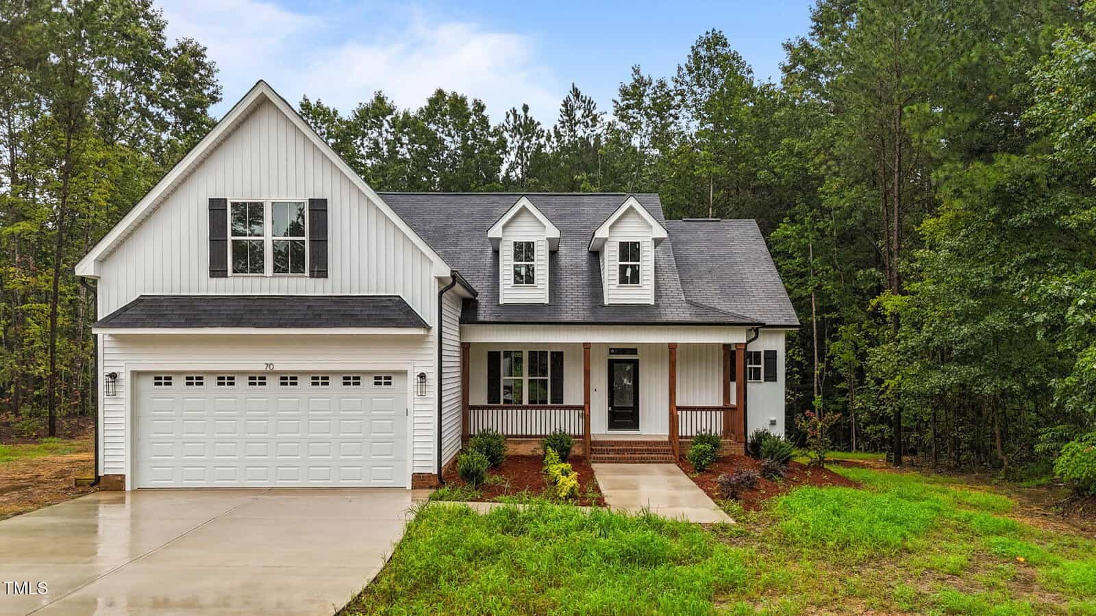 A white two-story house on 70 Copper Penny Road in Zebulon, featuring a double garage, a covered front porch, dormer windows, and a paved driveway, surrounded by green grass and trees in the background.