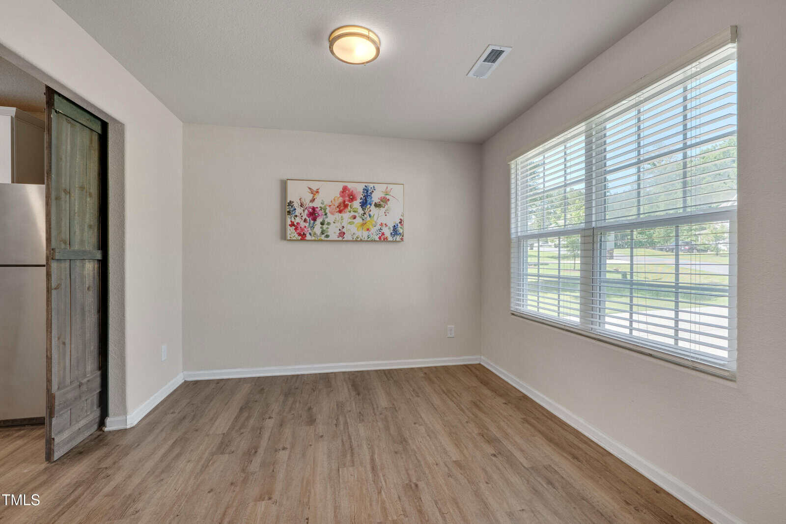 A room with a wood floor and a painting on the wall.