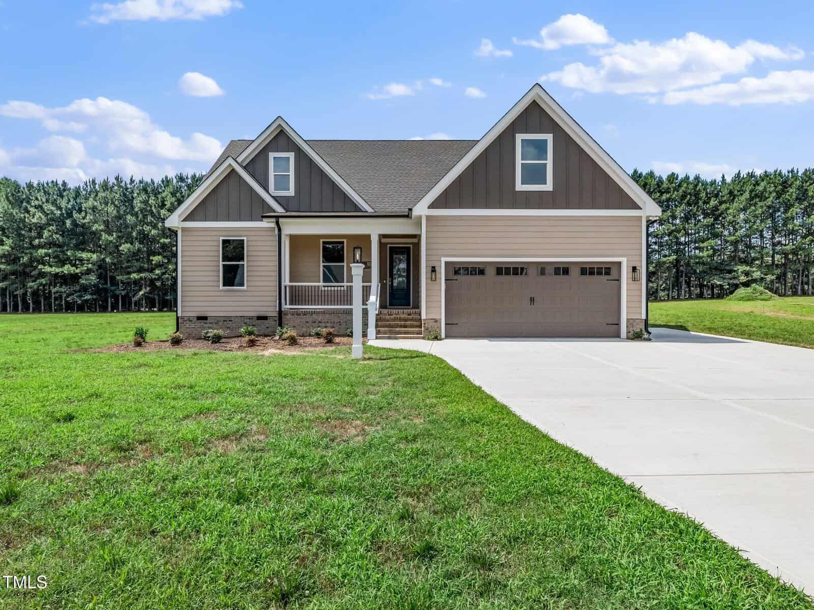 Single-story house with beige and brown siding, a covered front porch, attached two-car garage, and a well-kept lawn. Located at 106 Viola Lane in Franklinton, the home sits on a large lot with trees in the background and a wide concrete driveway in front.