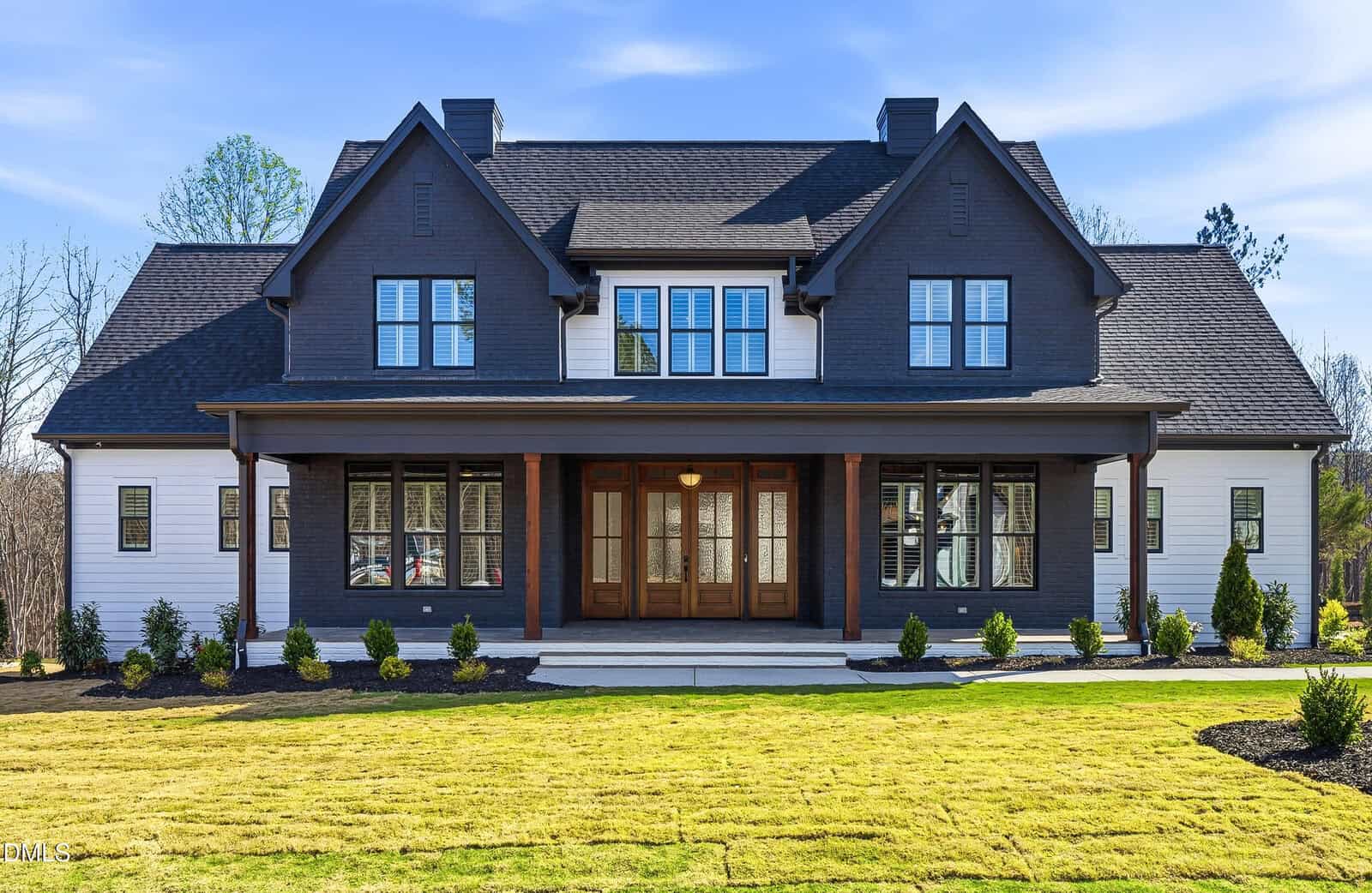 A large, modern two-story house at 3916 Cedar Knolls Drive in Youngsville features dark upper siding, white lower siding, a covered front porch with wooden columns, abundant windows, and a newly landscaped lawn.