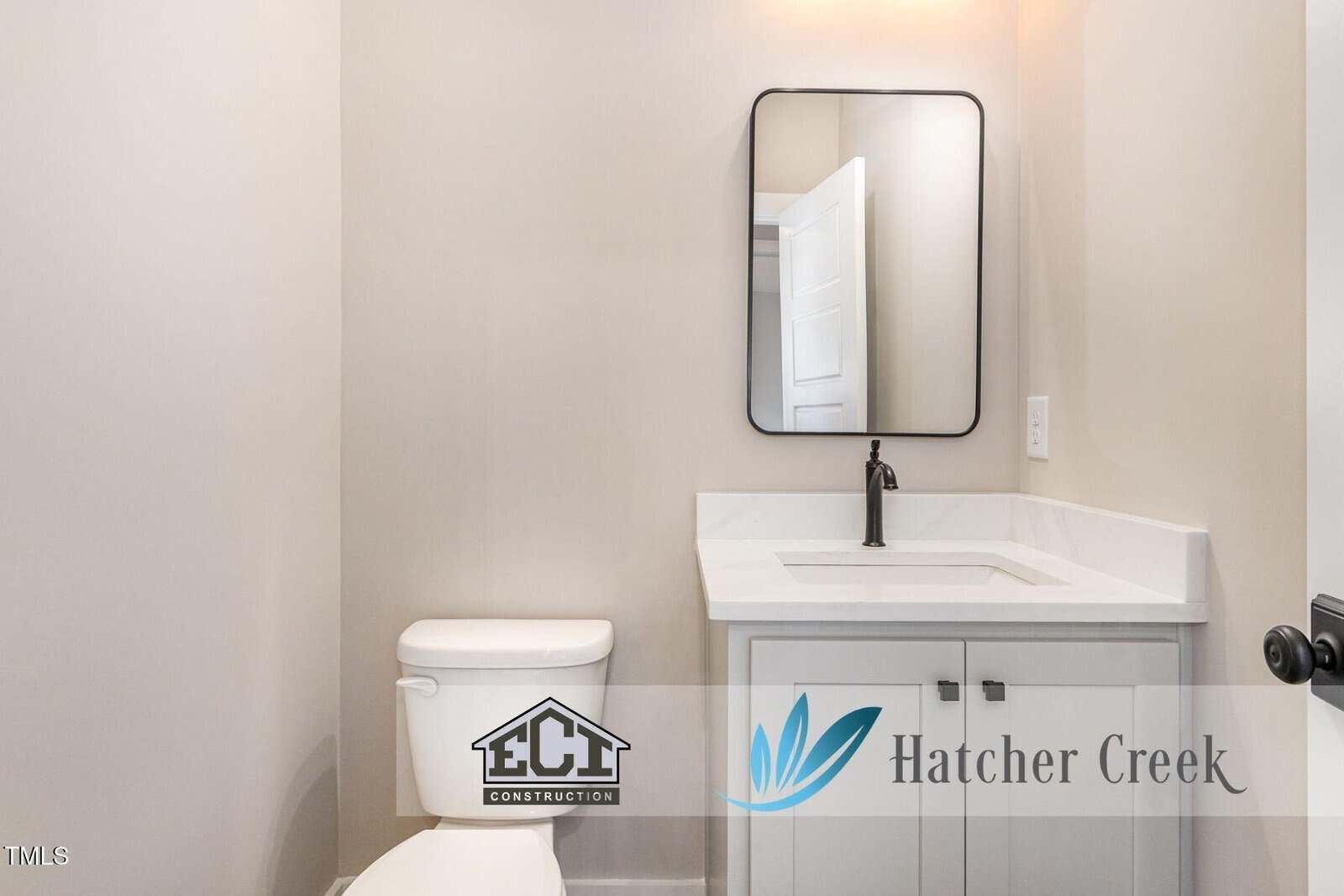 A small modern bathroom with a white toilet, white vanity with sink, black faucet, rectangular mirror, and neutral walls. Logos for ECI Construction and Hatcher Creek are overlaid.