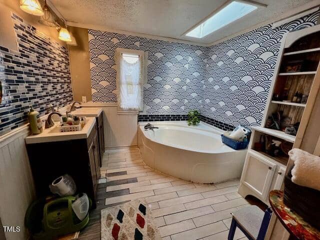 Bathroom with patterned tile walls, a corner bathtub, black sink vanity, open shelves with towels, and a mix of tile flooring. A small window and a ceiling skylight provide natural light.
