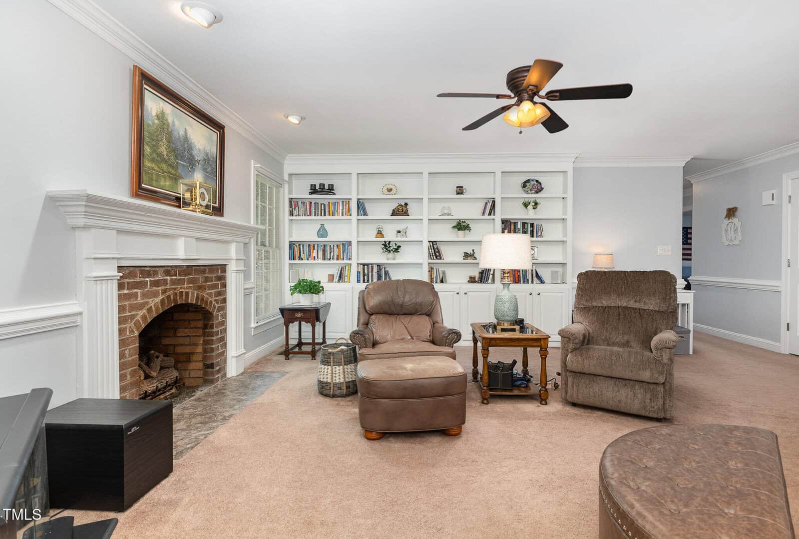 A living room with a fireplace and a fan.