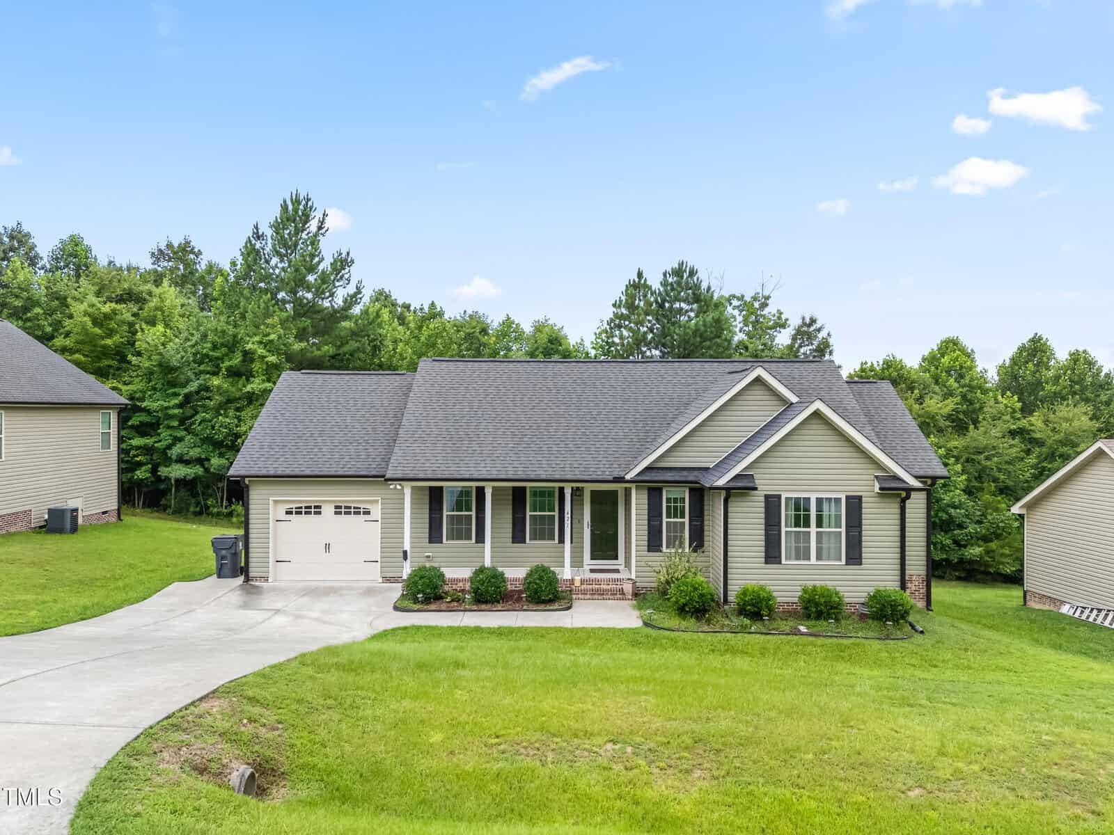 A single-story house at 421 Angus Place in Stem features gray siding, a dark roof, an attached single-car garage, front porch with white columns, and a well-kept lawn on a sloped driveway with trees and other homes in the background.