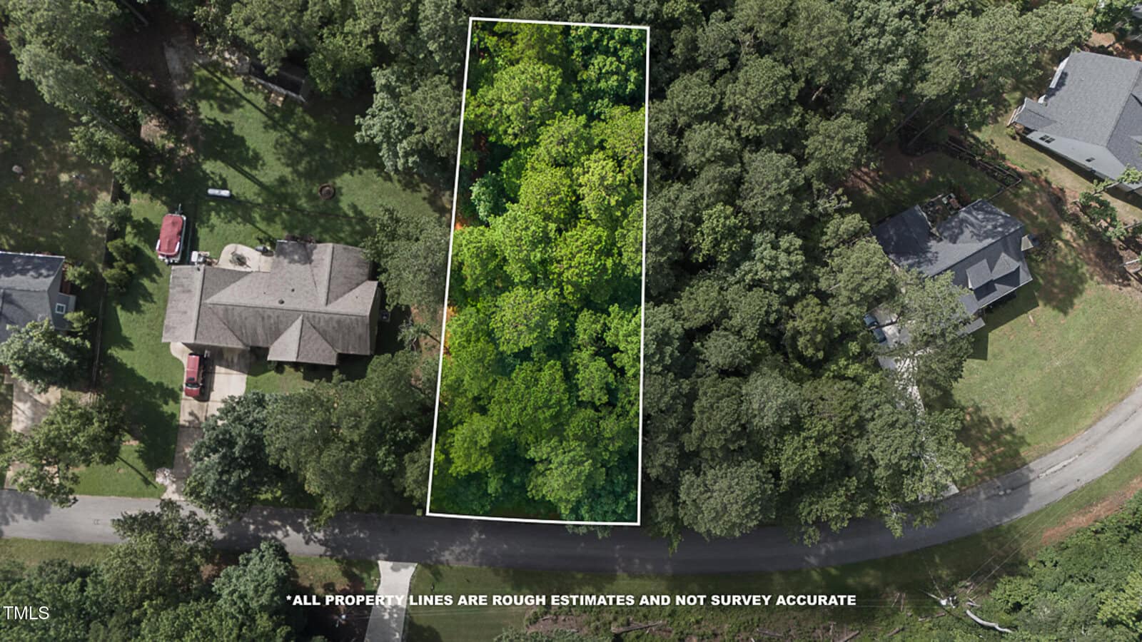 Aerial view of a wooded, rectangular lot outlined in white, surrounded by trees and neighboring houses on either side, with a curved road running along the bottom edge. Text notes property lines are rough estimates.
