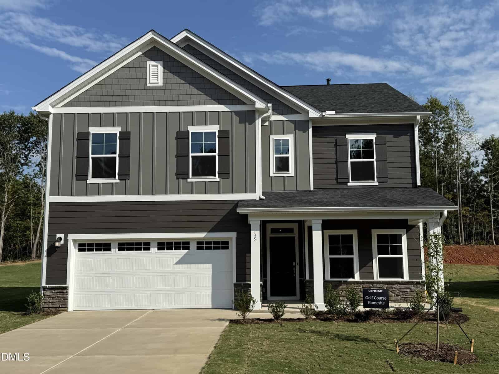 Two-story modern house with gray siding, white trim, black shutters, and a two-car garage located at 135 Venture Court in Franklinton. A sign in front indicates golf course homesites. The house sits on a concrete driveway with minimal landscaping. Trees in the background.