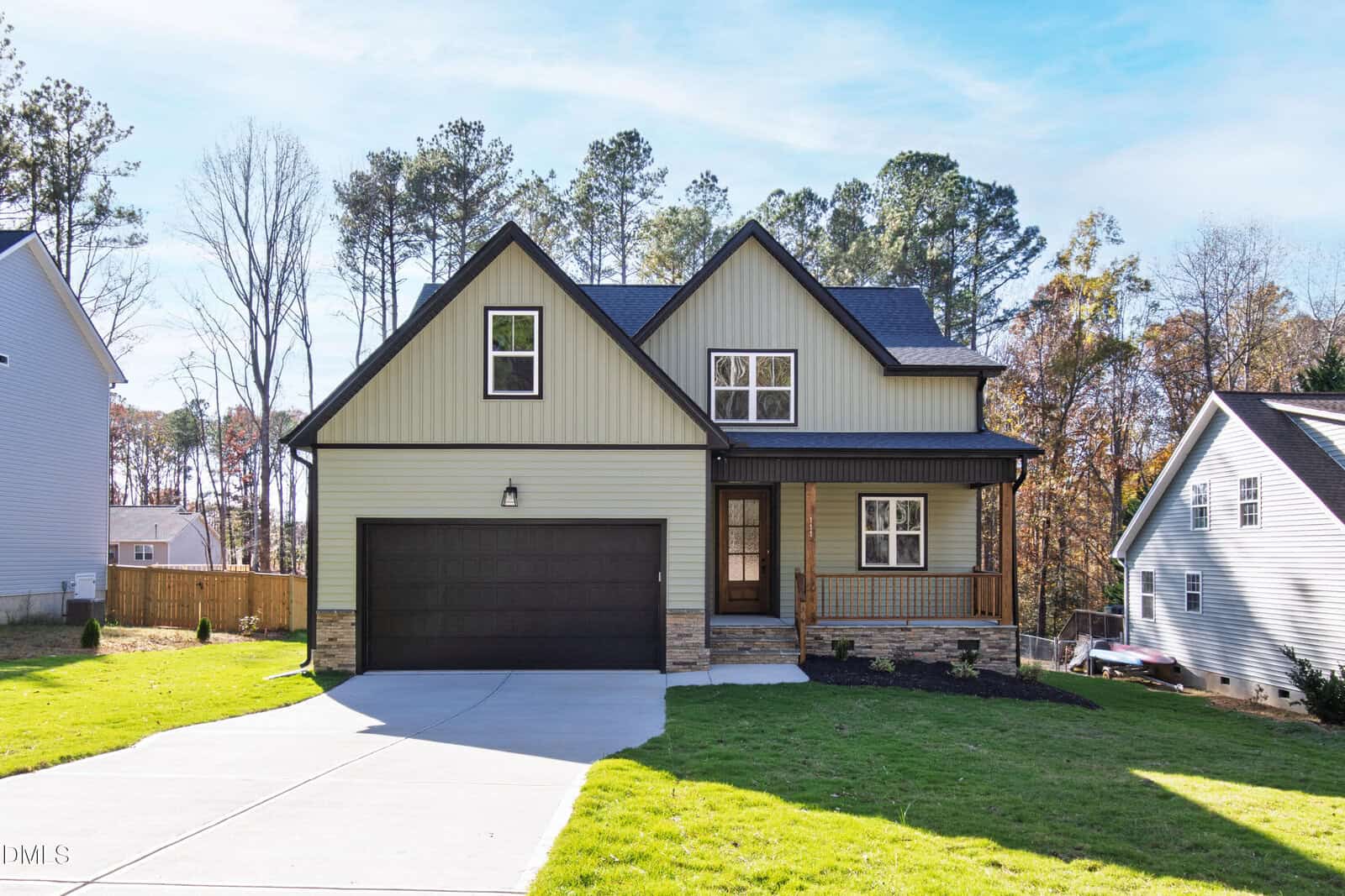 A two-story suburban house at 111 Mohawk Drive, Louisburg, with a large driveway, double garage, and front porch. The home features gray siding, stone accents, a neatly trimmed lawn, and is surrounded by trees and neighboring homes.