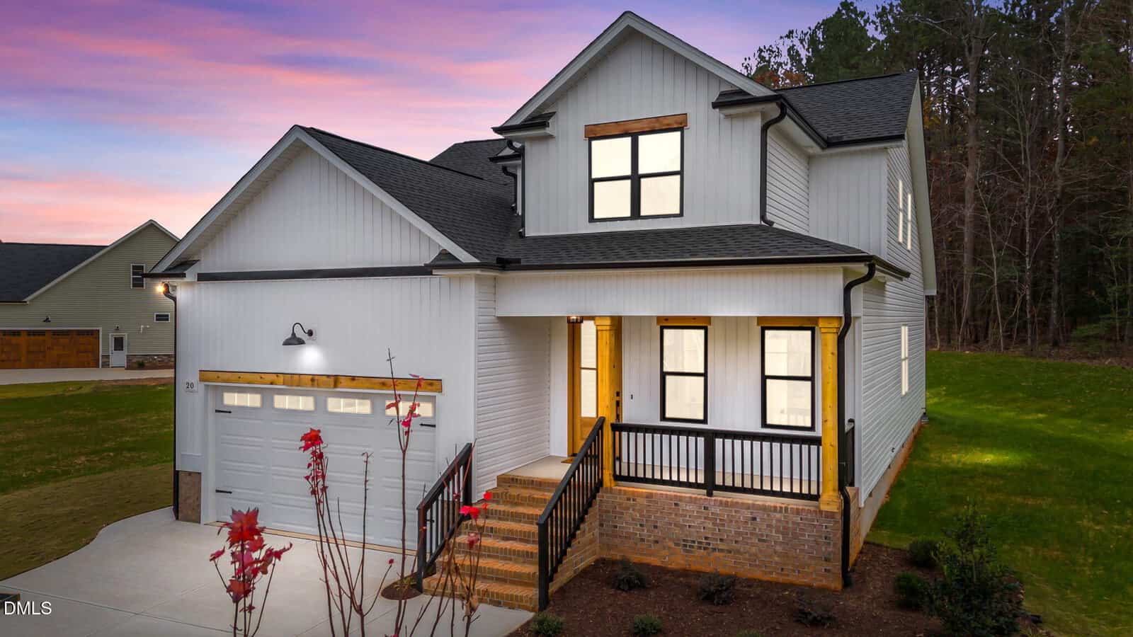 A modern two-story house at 20 Stream View Way in Zebulon, with a front porch, attached garage, and illuminated windows at dusk. The sky glows purple and pink, and the home is surrounded by grass and trees.