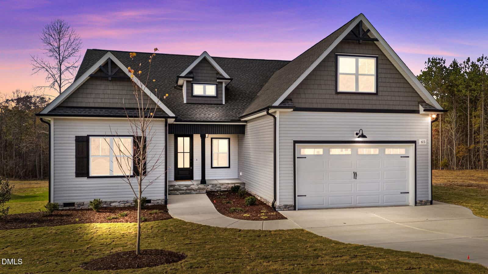 A modern, single-family house at 65 Livingston Lane in Zebulon features gray siding, black trim, and a two-car garage on a manicured lawn at sunset, with a small tree and forest in the background.