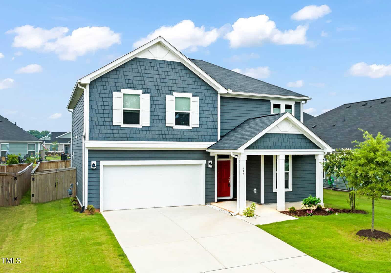 Located in Youngsville at 215 Purple Aster Street, this two-story modern house features dark blue siding, white trim, a double garage, and a welcoming covered porch. Enjoy a manicured lawn and beautiful landscaping surrounding the home.