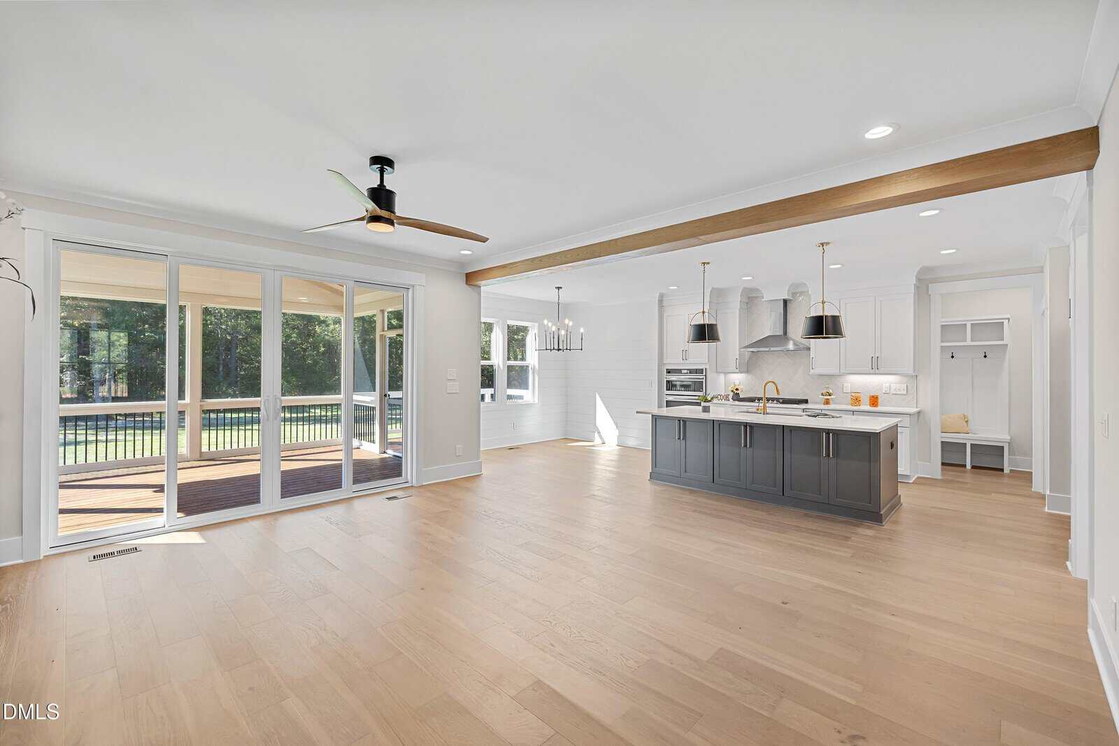 A large white and grey kitchen with a wood floor and ceiling fan.