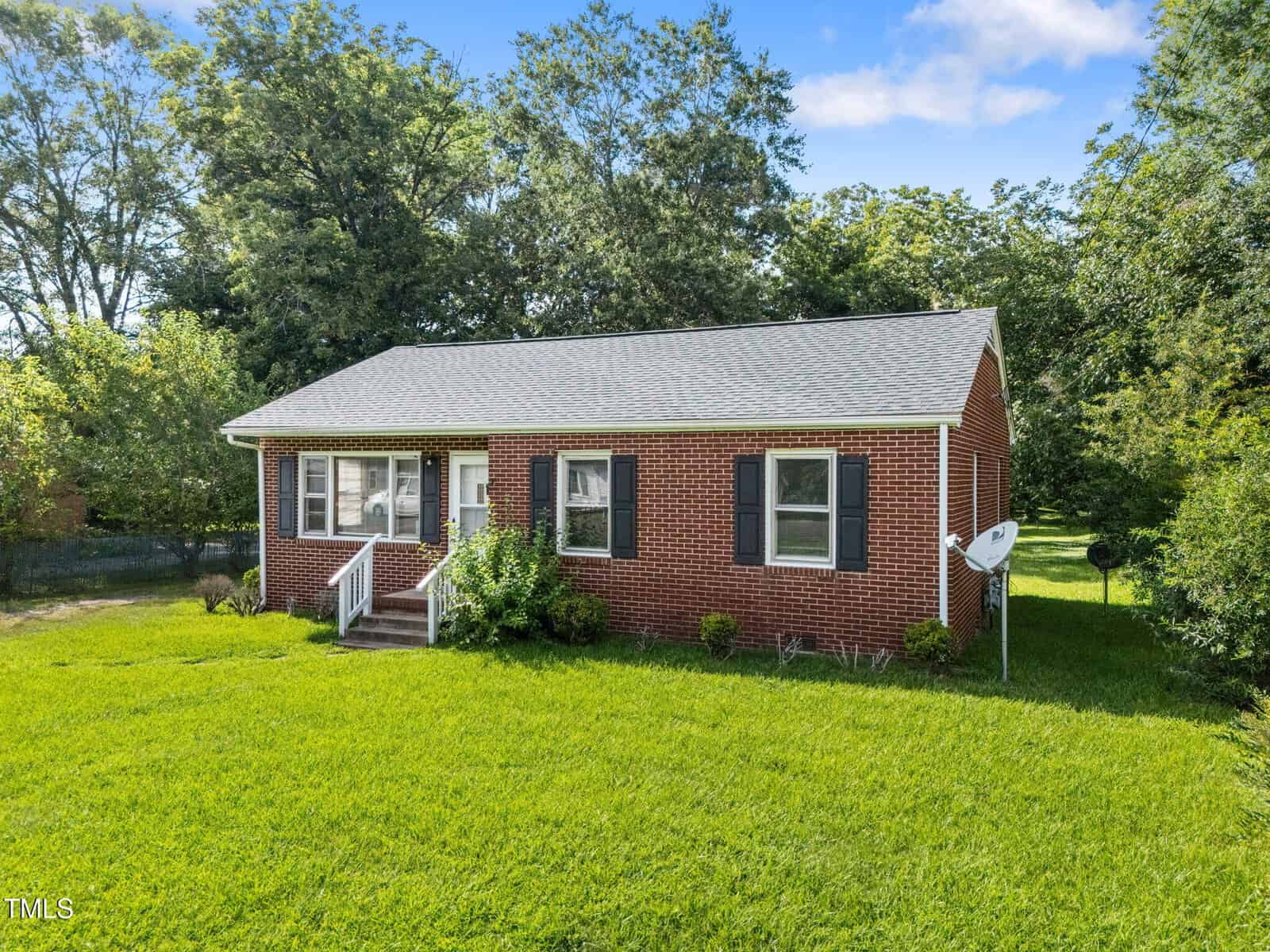A brick house with a lawn and trees in the background.