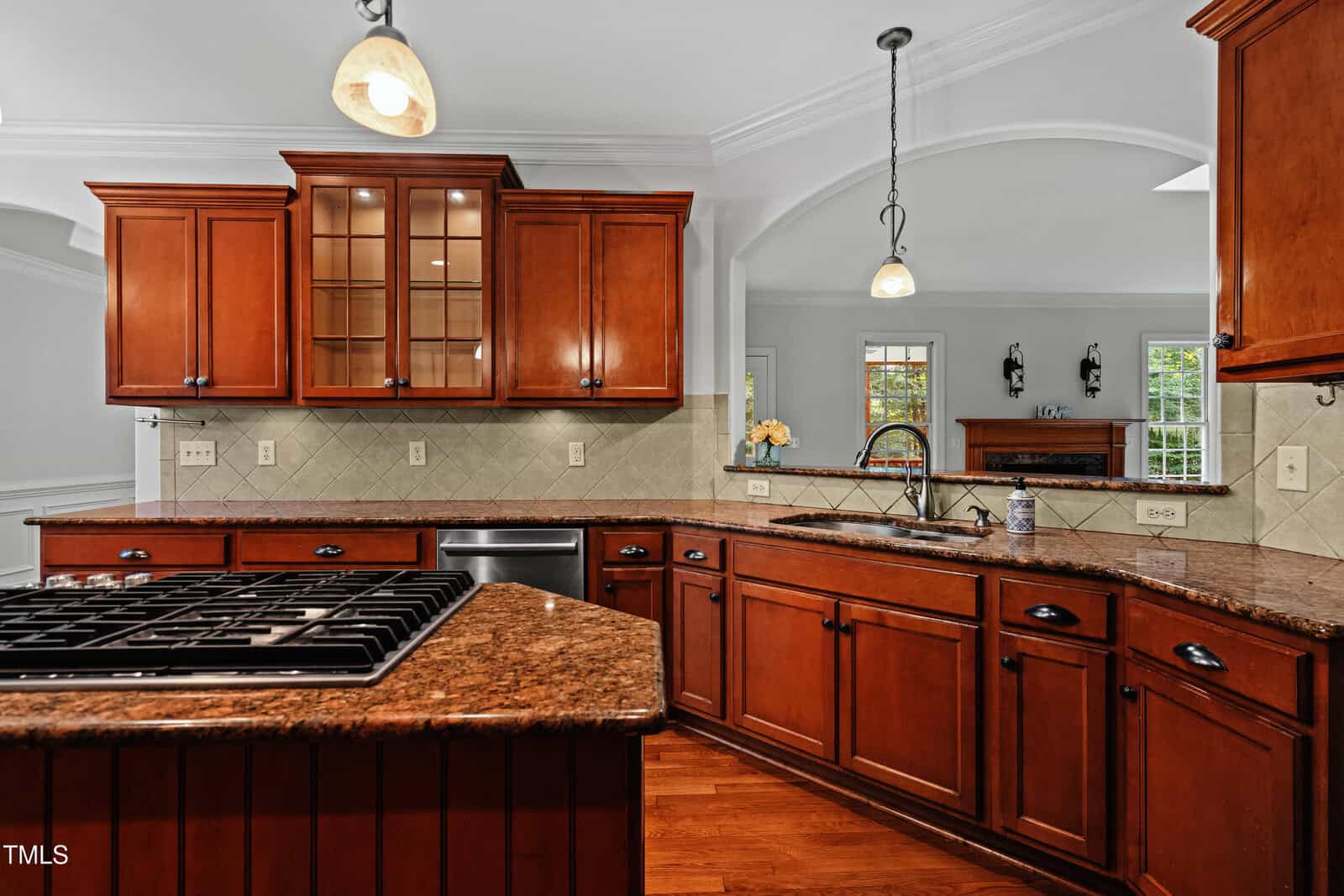 Spacious kitchen with wooden cabinets, granite countertops, stainless steel appliances, tile backsplash, and pendant lighting above the sink area.