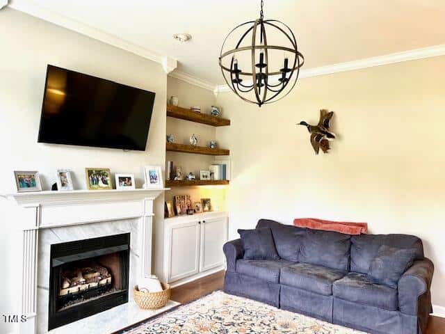 A cozy living room with a blue couch, a wall-mounted TV above a white fireplace, built-in shelves with photos and decor, a decorative chandelier, and a duck wall sculpture.