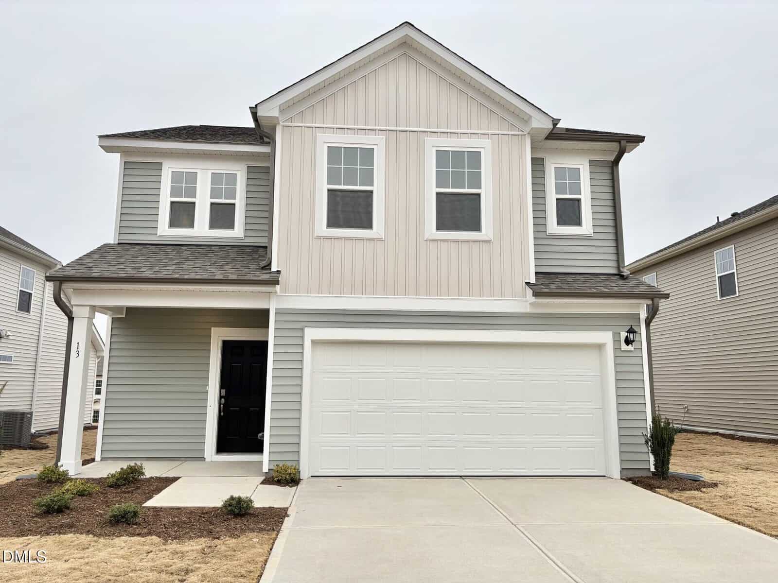 Two-story suburban house at 13 Gerrad Street, Franklinton, with light gray and beige vertical siding, white trim, double garage, black front door, small front porch, minimal landscaping, and an overcast sky.
