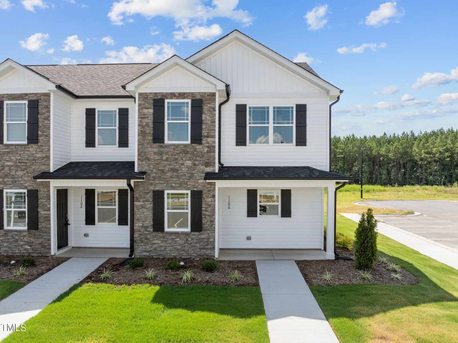 A two-story townhouse at 1106 Brookrun Drive, Oxford, features stone and white siding, black shutters, and a covered front porch. The landscaped yard includes grass and small shrubs, with a driveway visible on the right.