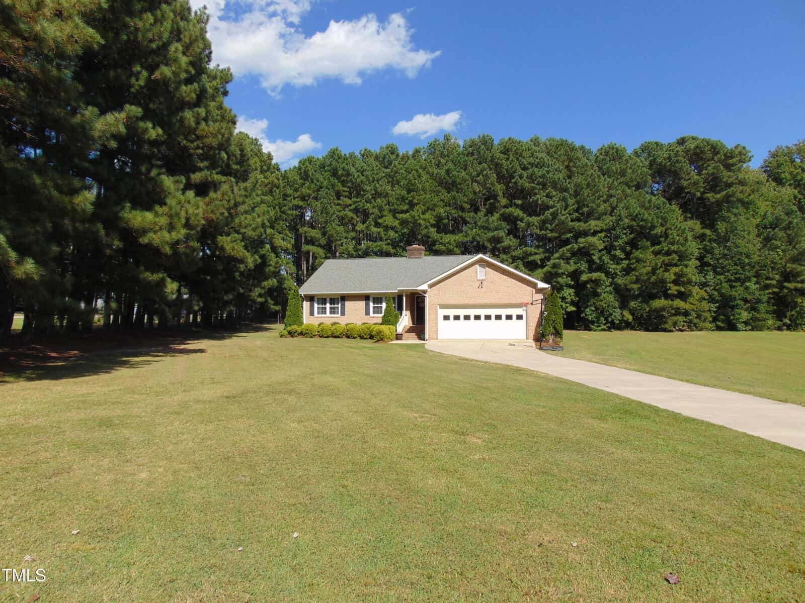 A house with a driveway and trees in the background with Town Creek Indian Mound in the background.