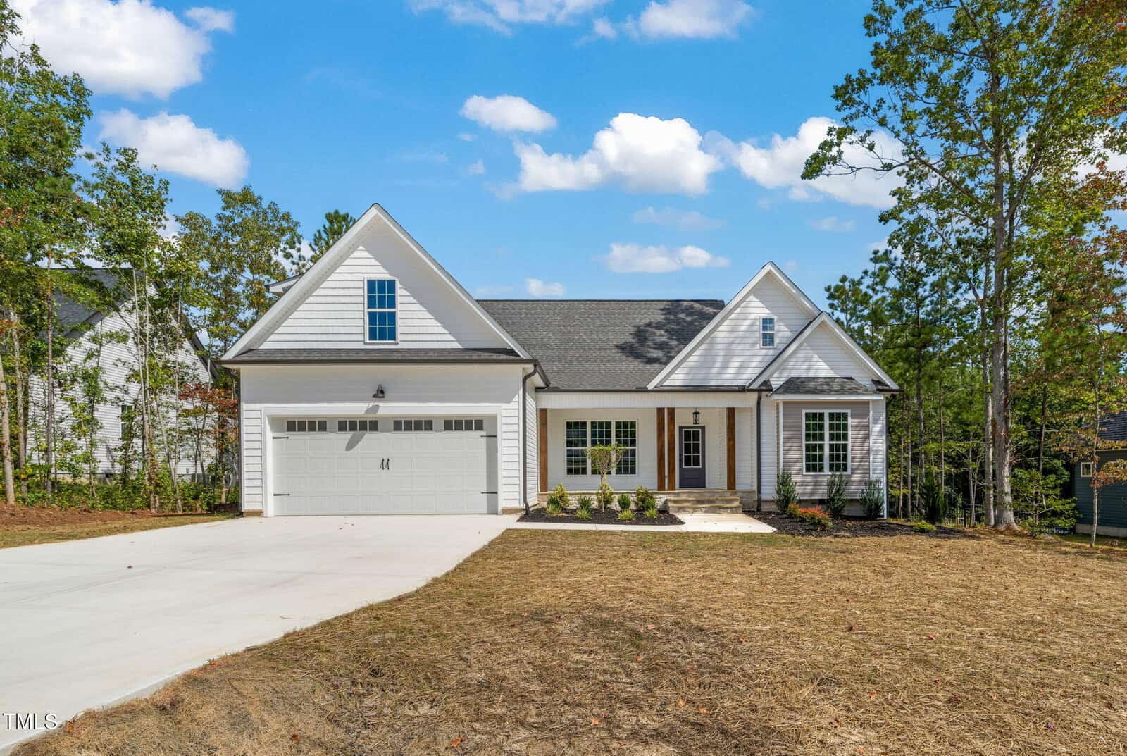 A modern single-story house at 130 Beauview Way, Zebulon, featuring gray siding, white trim, and a spacious two-car garage. The house boasts a welcoming front porch, multiple windows for ample natural light, and a large concrete driveway. Trees and a well-kept lawn area surround the property, enhancing its curb appeal.