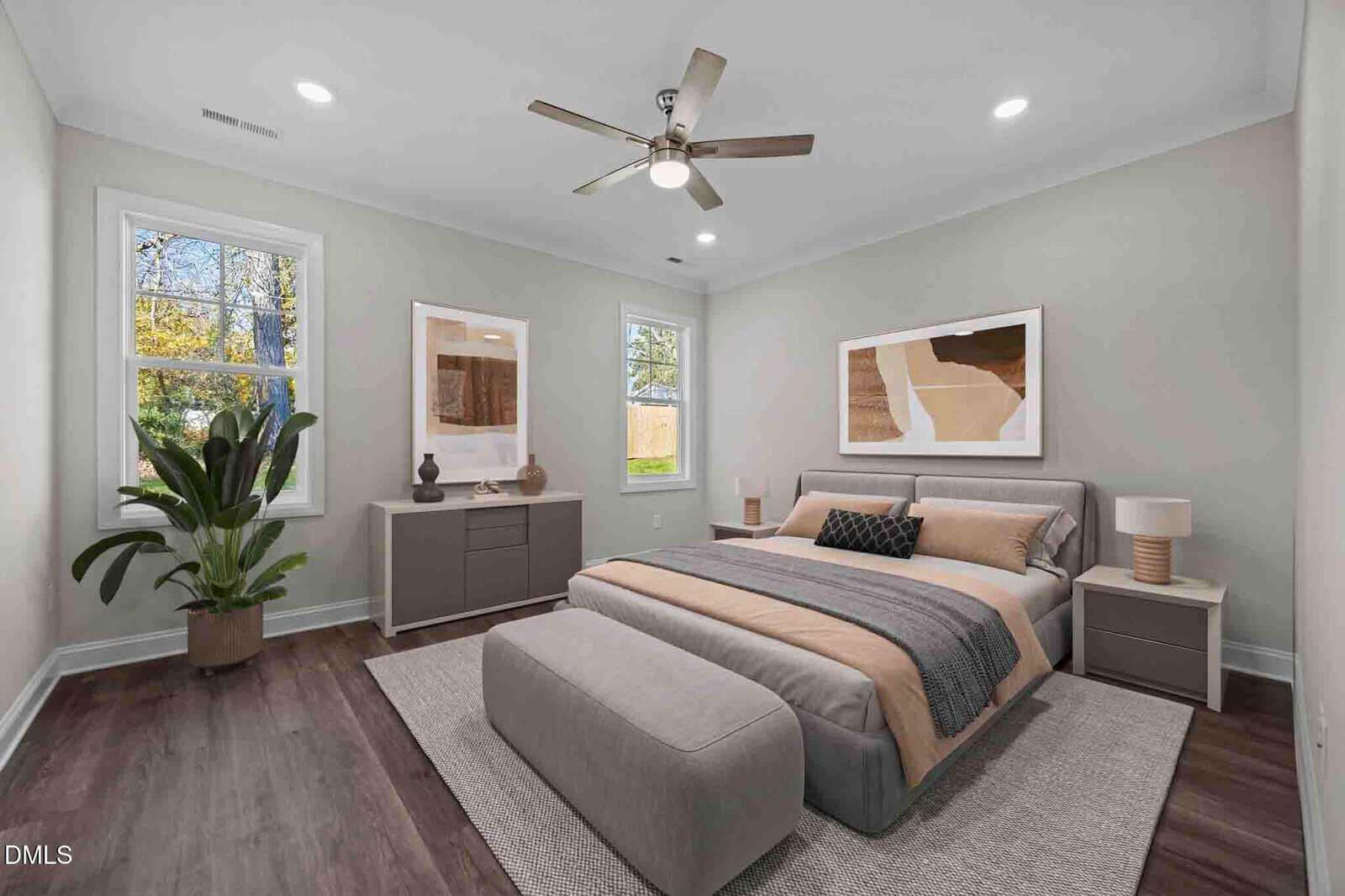 Modern bedroom with a large bed, two nightstands, artwork on the walls, a dresser, a large plant by the window, and a ceiling fan. The room has wood flooring and neutral-toned decor.
