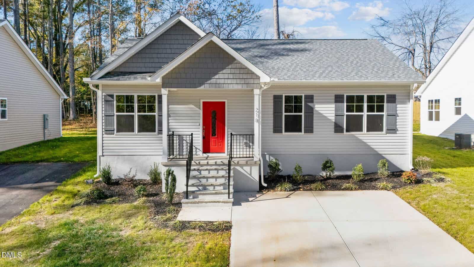 Charming single-story gray home in Franklinton, located at 218 E College Street, featuring a gabled roof, bold red front door, white trim, concrete driveway, small front porch, and minimal front yard landscaping.