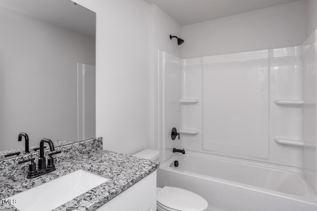 Modern bathroom with a granite countertop vanity, black fixtures, and a white bathtub-shower combo with built-in shelves. The walls are white, creating a clean and minimalist look.