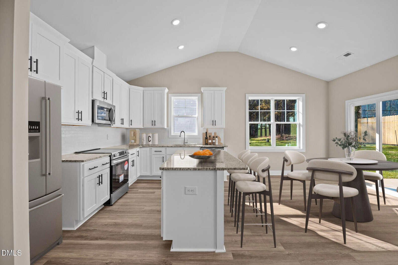 Modern kitchen with white cabinets, stainless steel appliances, a large island with bar stools, and a dining area by a window. Sunlight streams in through windows, highlighting light wood floors and neutral walls.