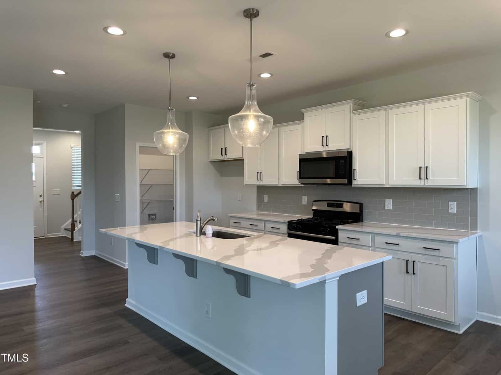 A kitchen with white cabinets and a white island.